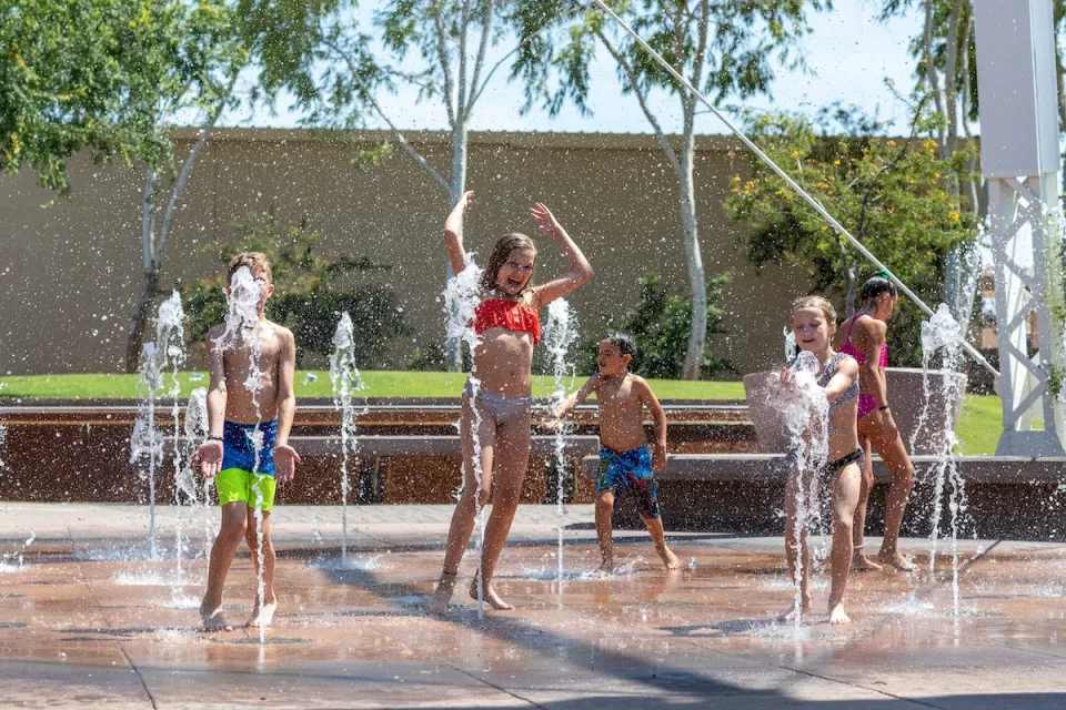 Group of children playing on splash pad in urban park.